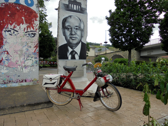 Un Vélosolex devant des vestiges du mur de Berlin